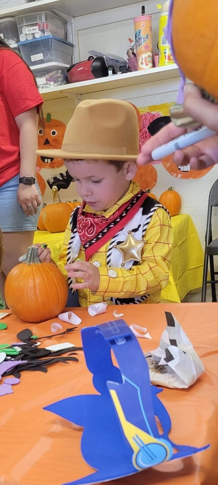 Child in cowboy costume decorating pumpkin