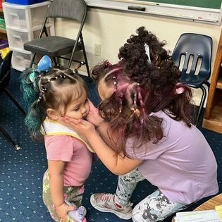 Teacher braiding child's hair in classroom
