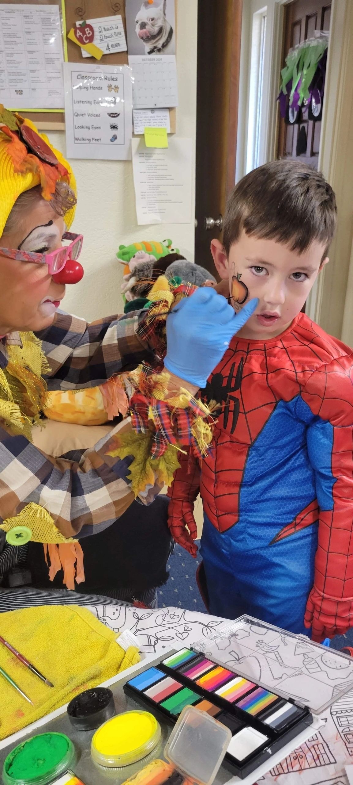 Clown applying face paint to child in costume