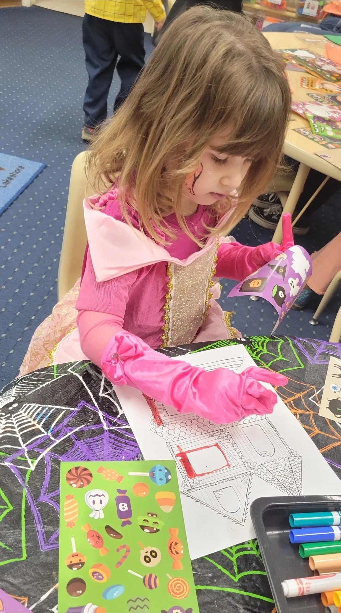Child coloring Halloween themed artwork in classroom