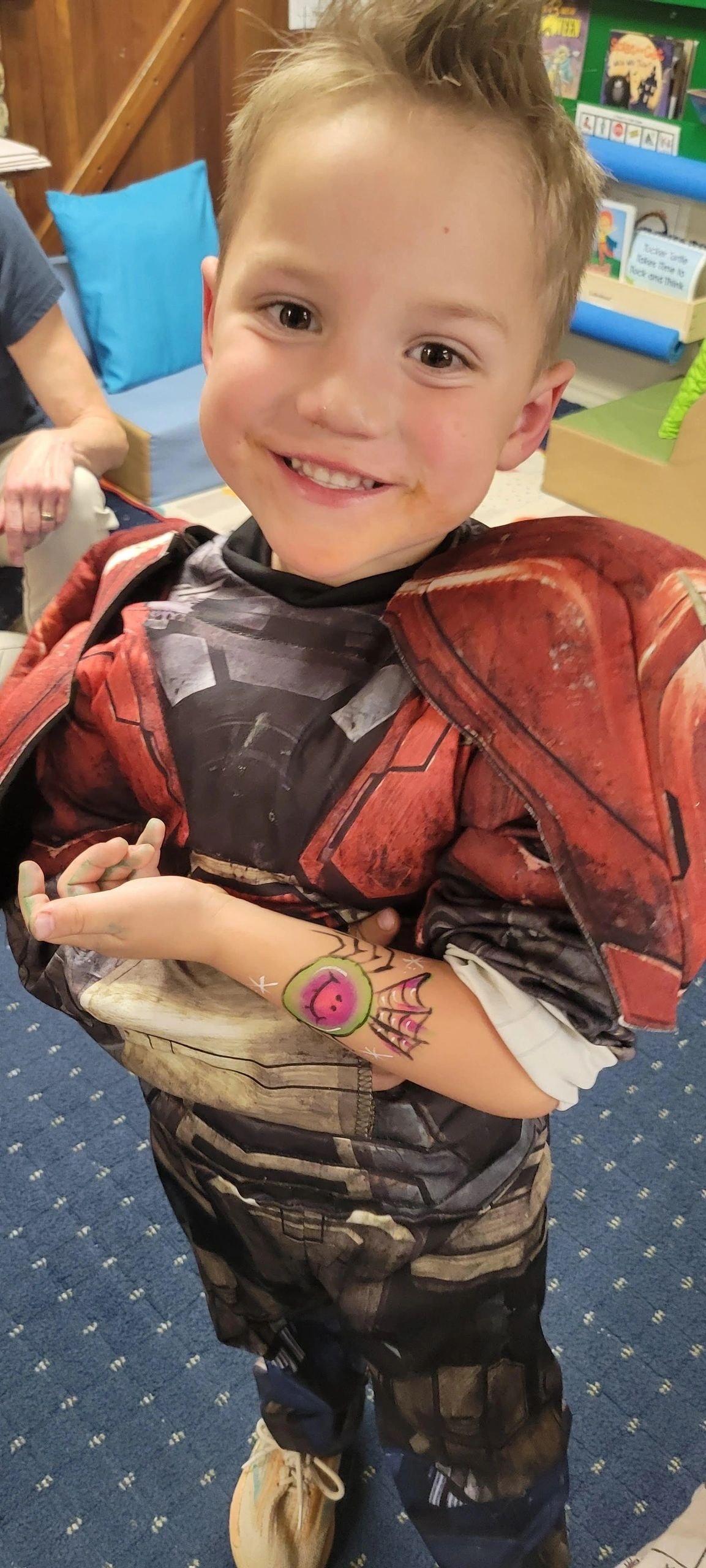 Child in superhero costume showing arm tattoo