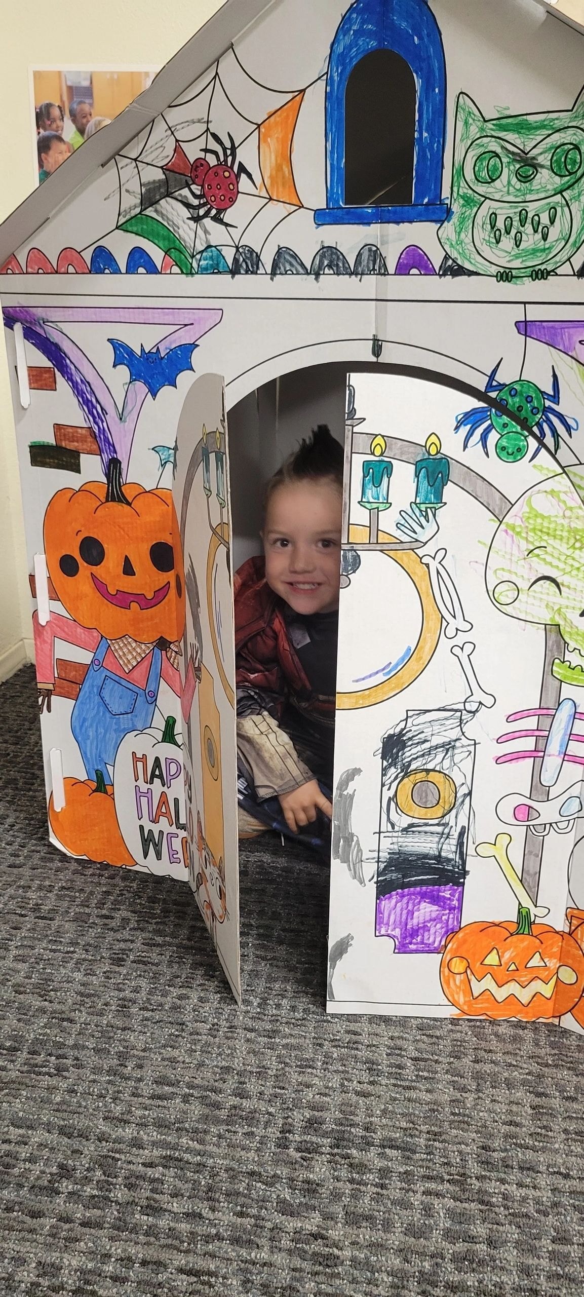 Child peeking from Halloween haunted house craft